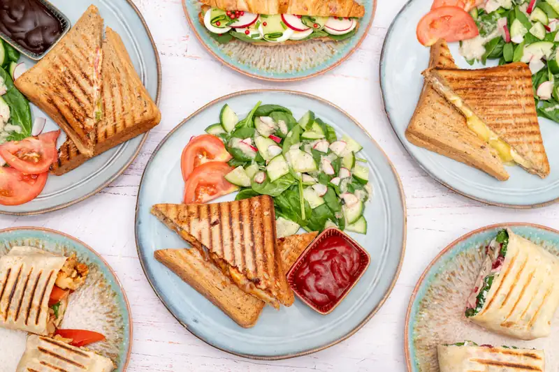 Grillowane tosty i wrapy z sałatką na talerzach